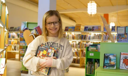 Barn som håller i böcker på biblioteket