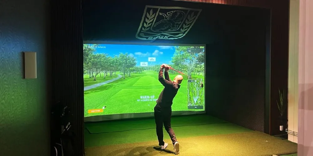 En man som svingar klubban i en golfsimulator