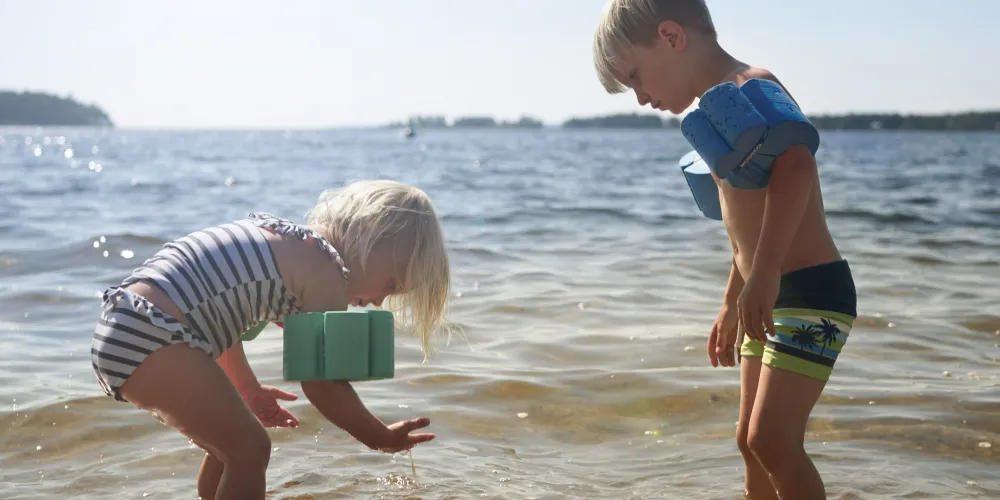 Barn som leker och badar i havet