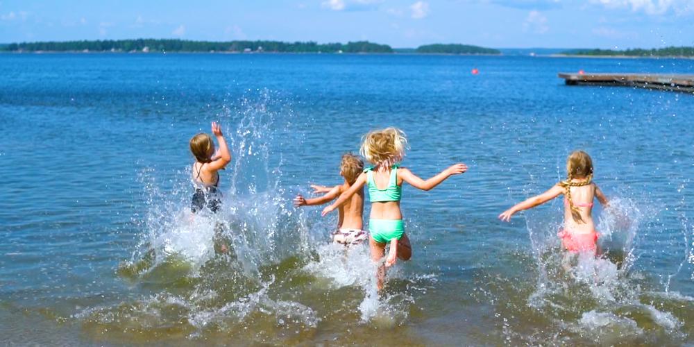 Barn som springer i vattnet på stranden, ön Enskär