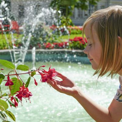 Ett barn tittar på blommor i Rådhusparken