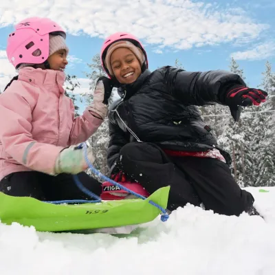 Barn som leker i snön och åker pulka