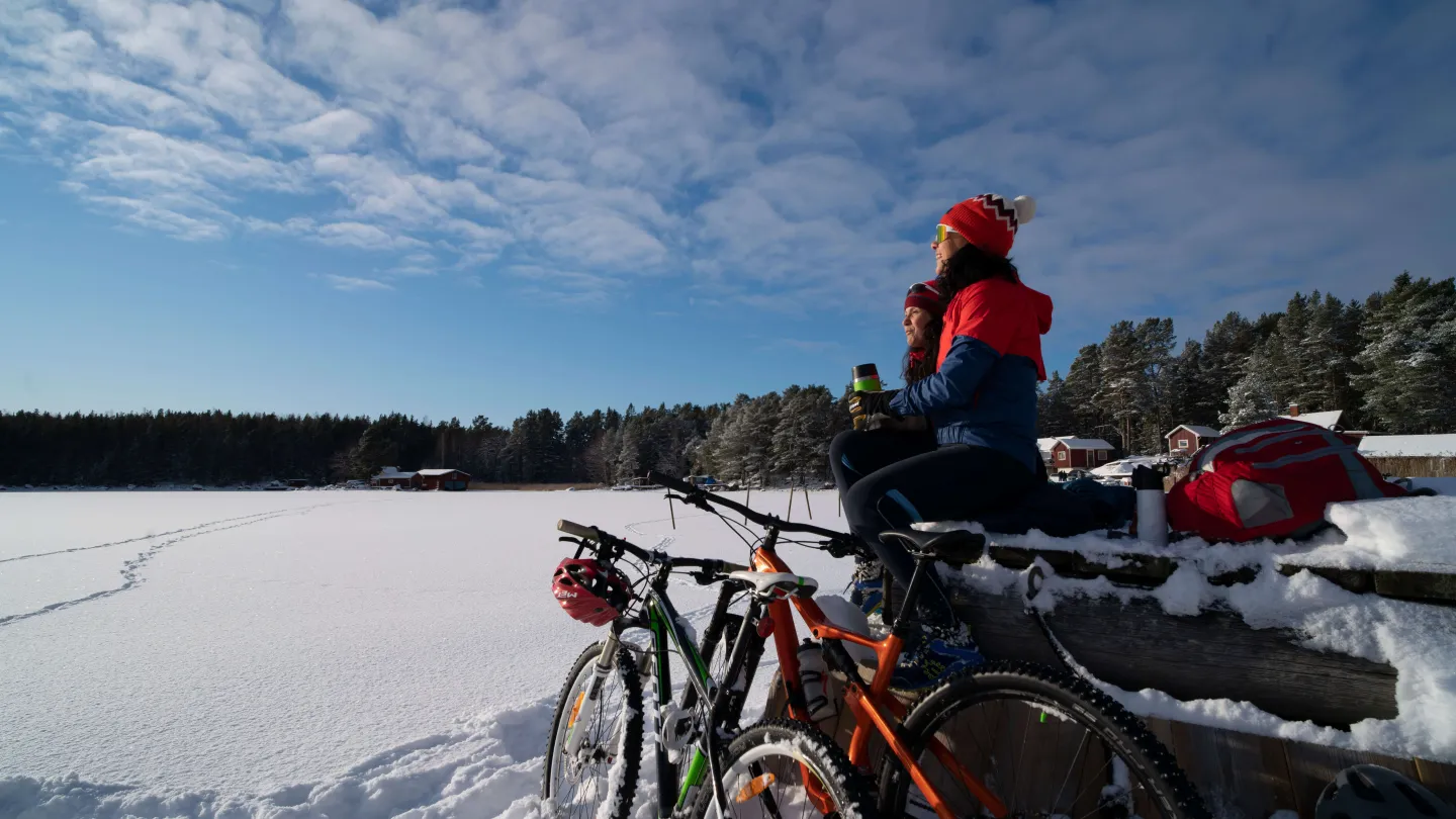 Vintercykling med fikapaus bredvid snötäckt hav