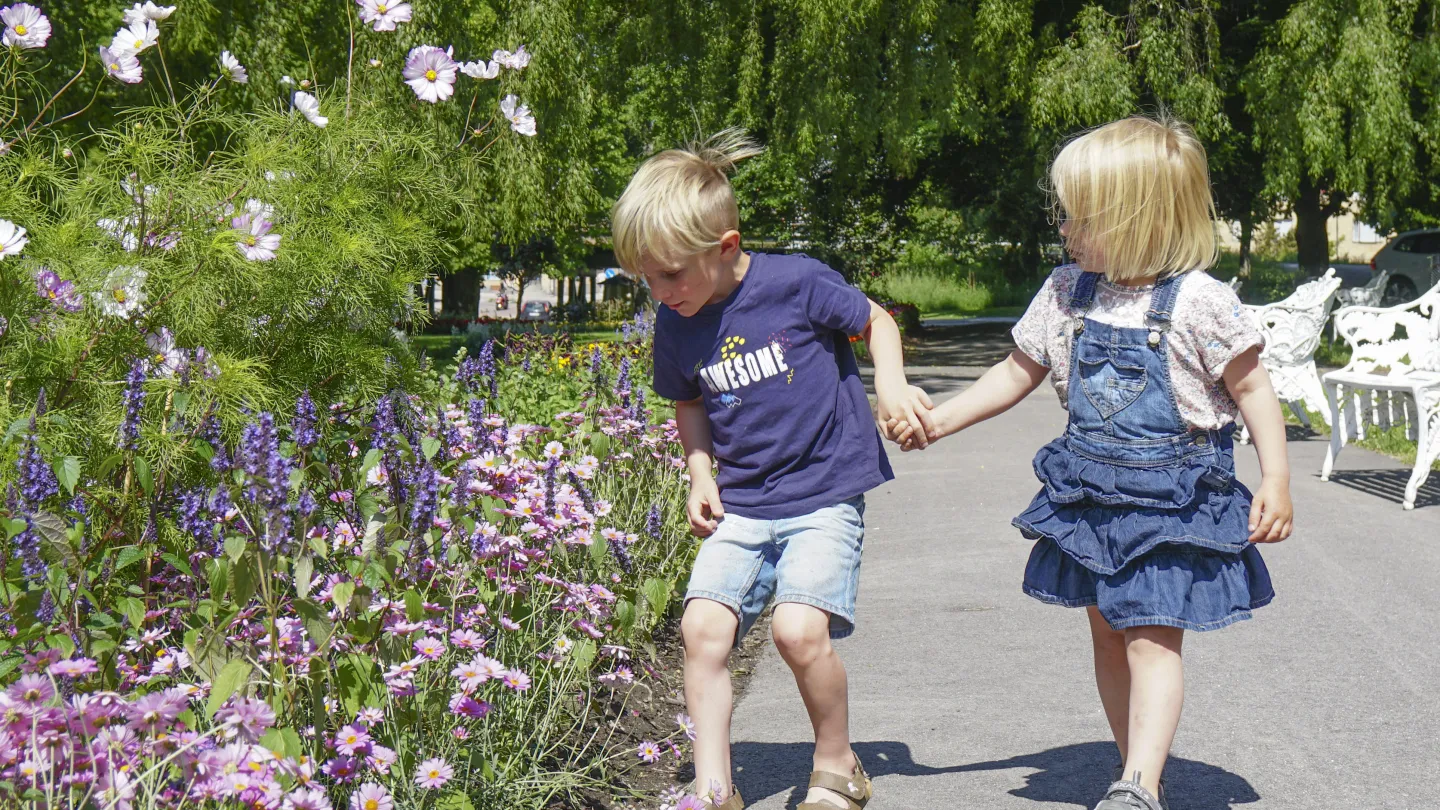 barn som luktar på blommor i parken