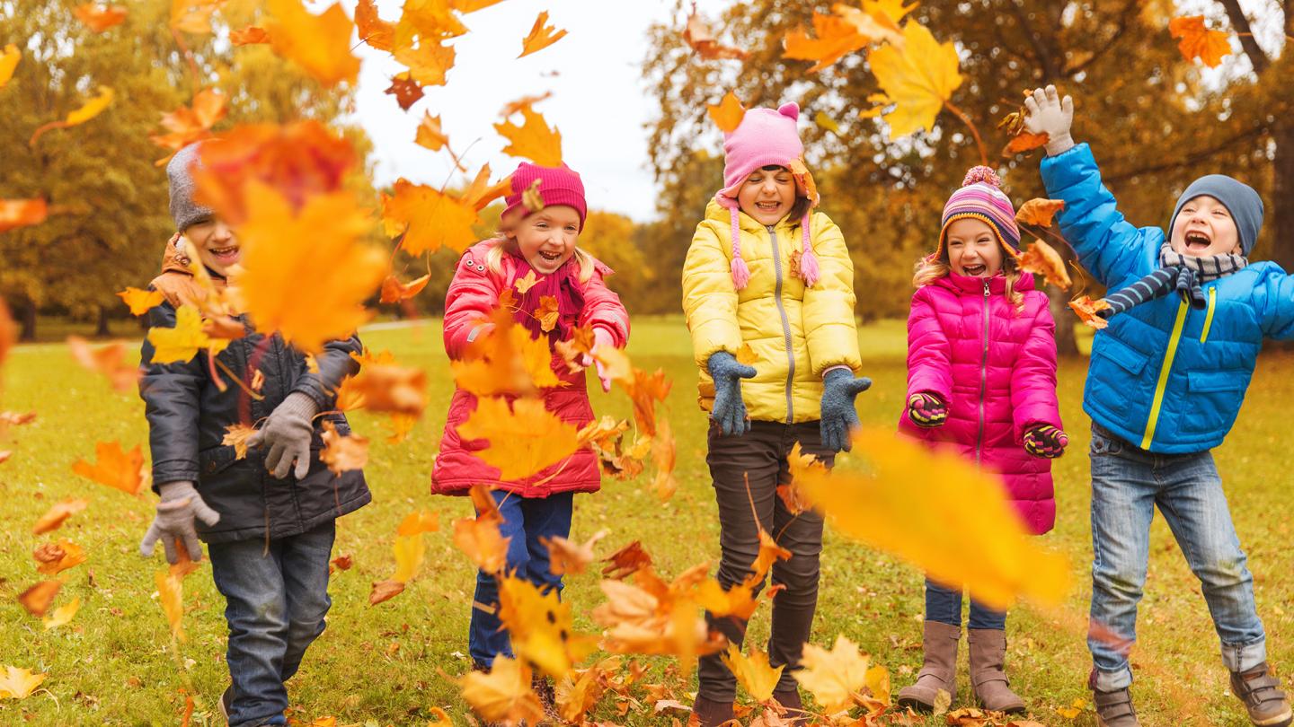 Barn som leker med löv utomhus på höstlovet