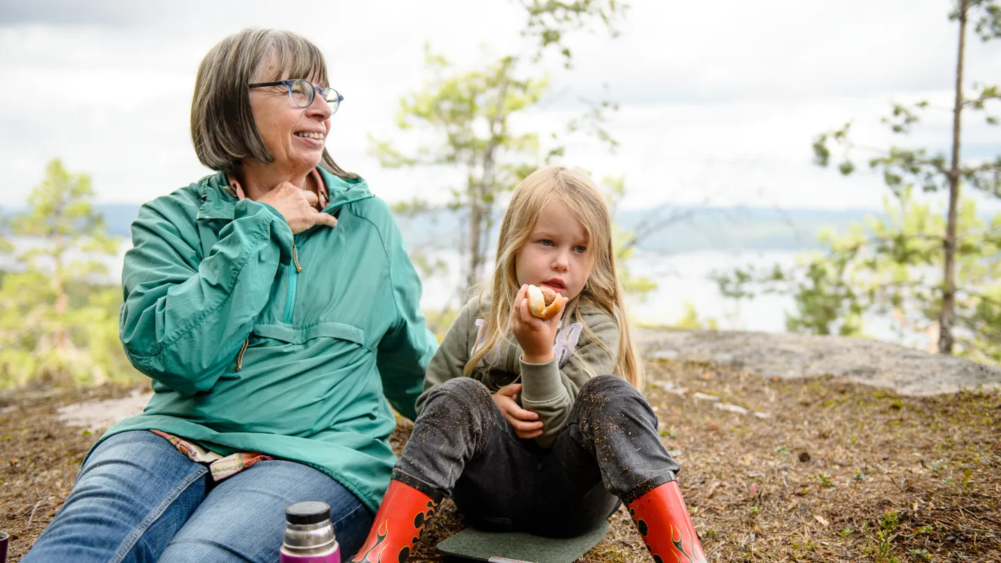 Barn och vuxen har en fikapaus vid utsiktsplats på höstvandring